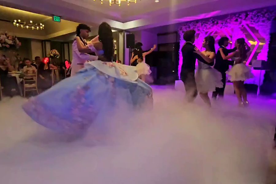 Vals de la quinceañera y su corte sobre niebla baja en la pista de baile